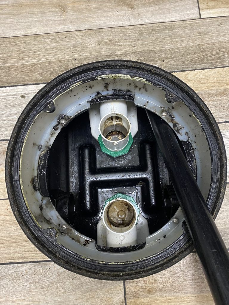 Empty and corroded commercial grease trap with broken baffle t requiring repair