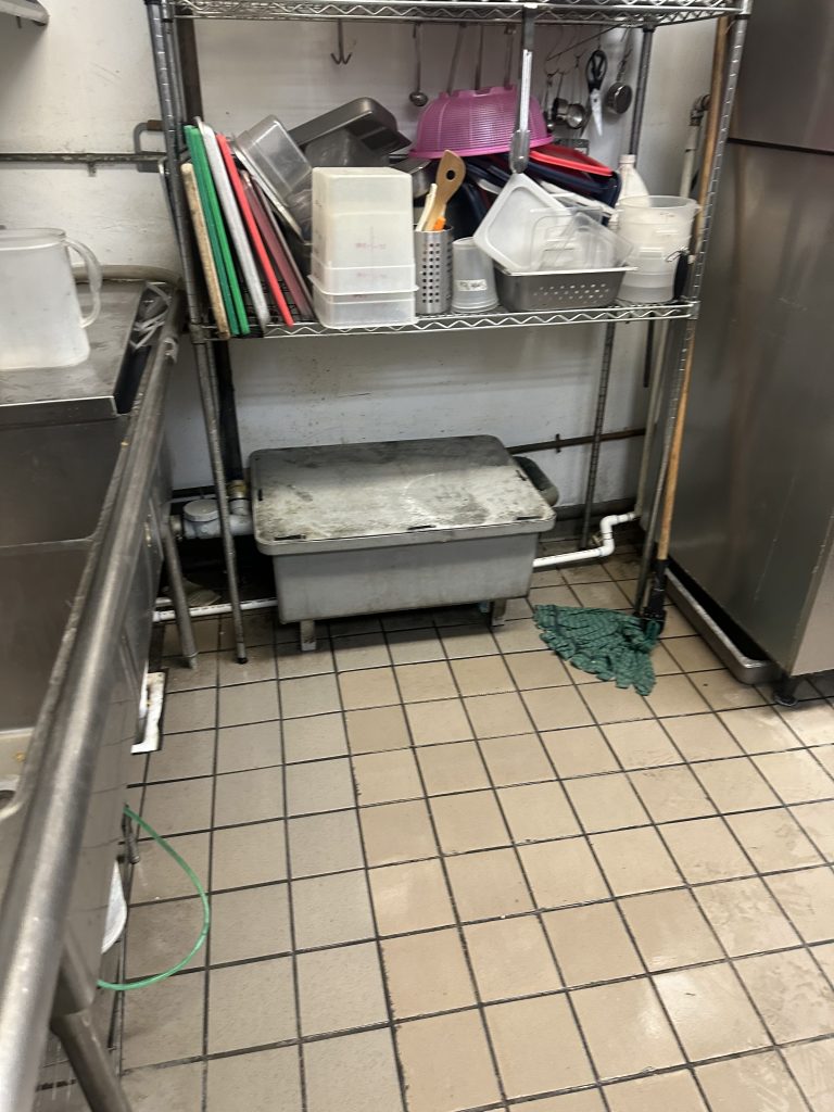 Commercial kitchen grease trap installed under a sink, ready for cleaning in San Diego County.