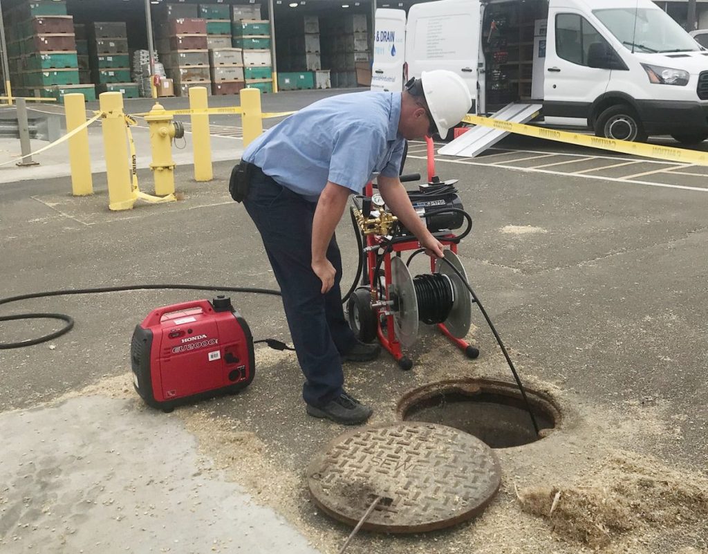 Technician performing a commercial drain cleaning operation using hydro jet equipment